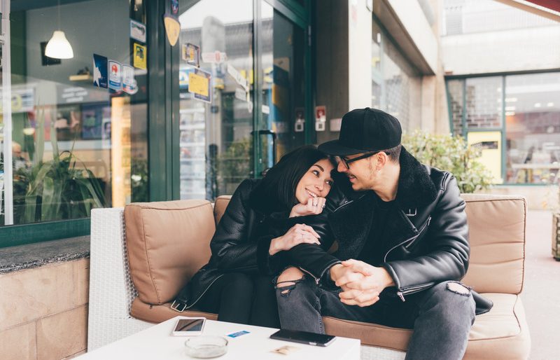 Young beautiful couple sitting outdoor hugging having fun - relationship, love, happiness concept